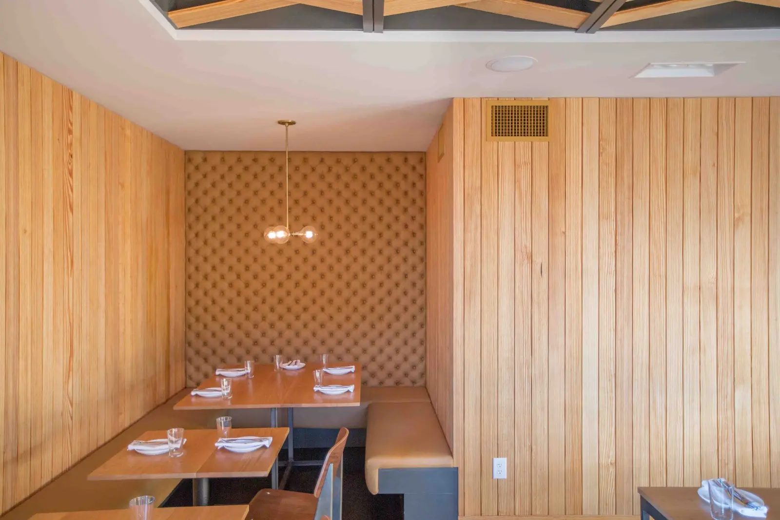 Unit-D Pizzaria dining nook with wood plank walls and a tufted wall