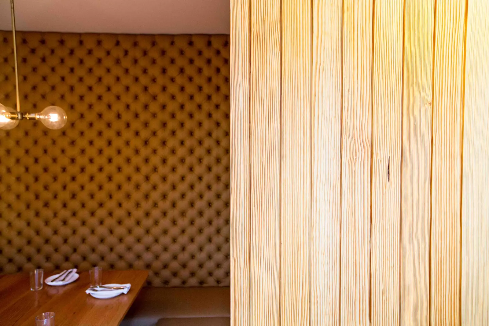 Unit-D Pizzaria booth with a tufted wall beside a wood plank wall