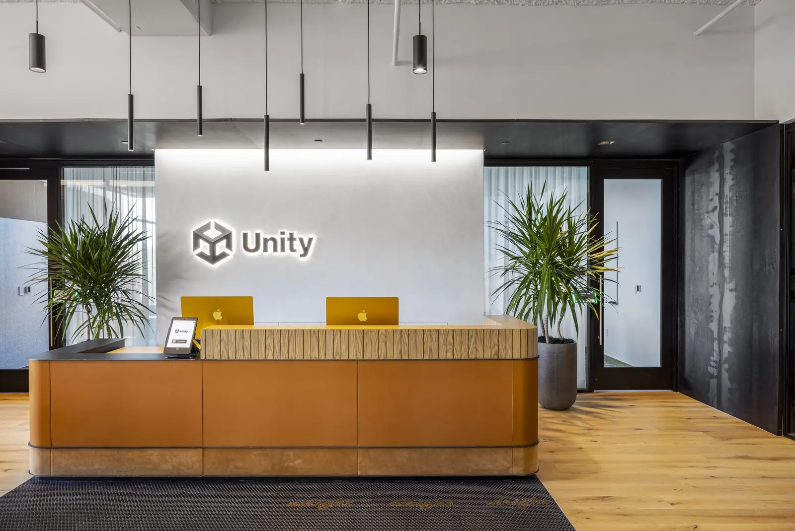 Unity reception desk with an orange front and a Unity logo wall