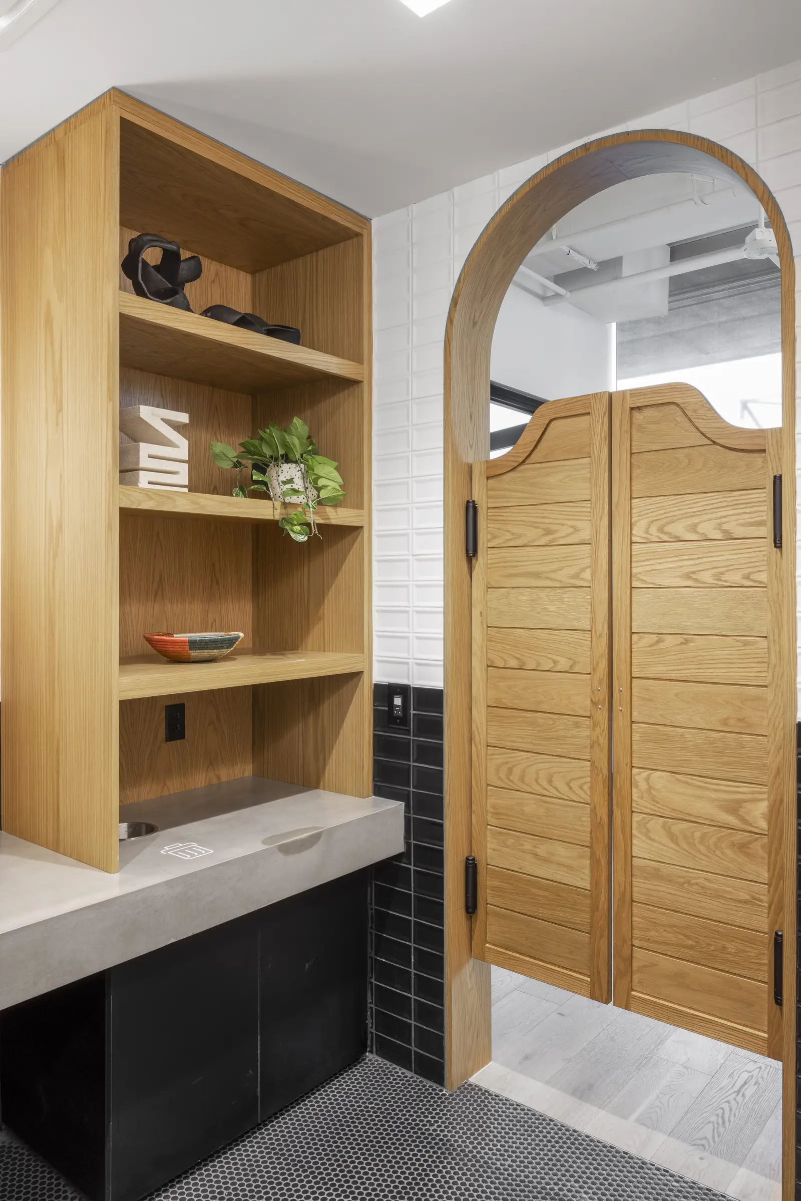 Unity wood built-in shelving beside arched swinging doors