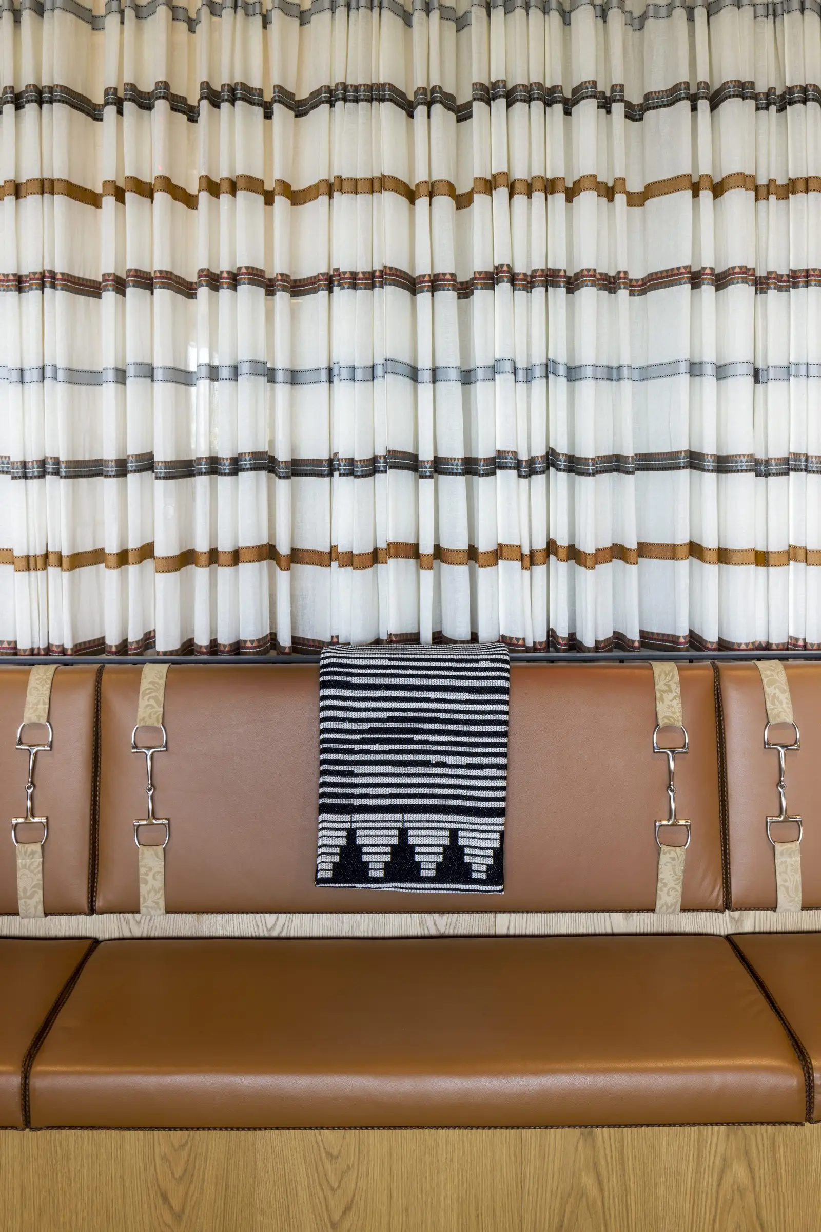 Unity leather bench seating beneath striped curtains