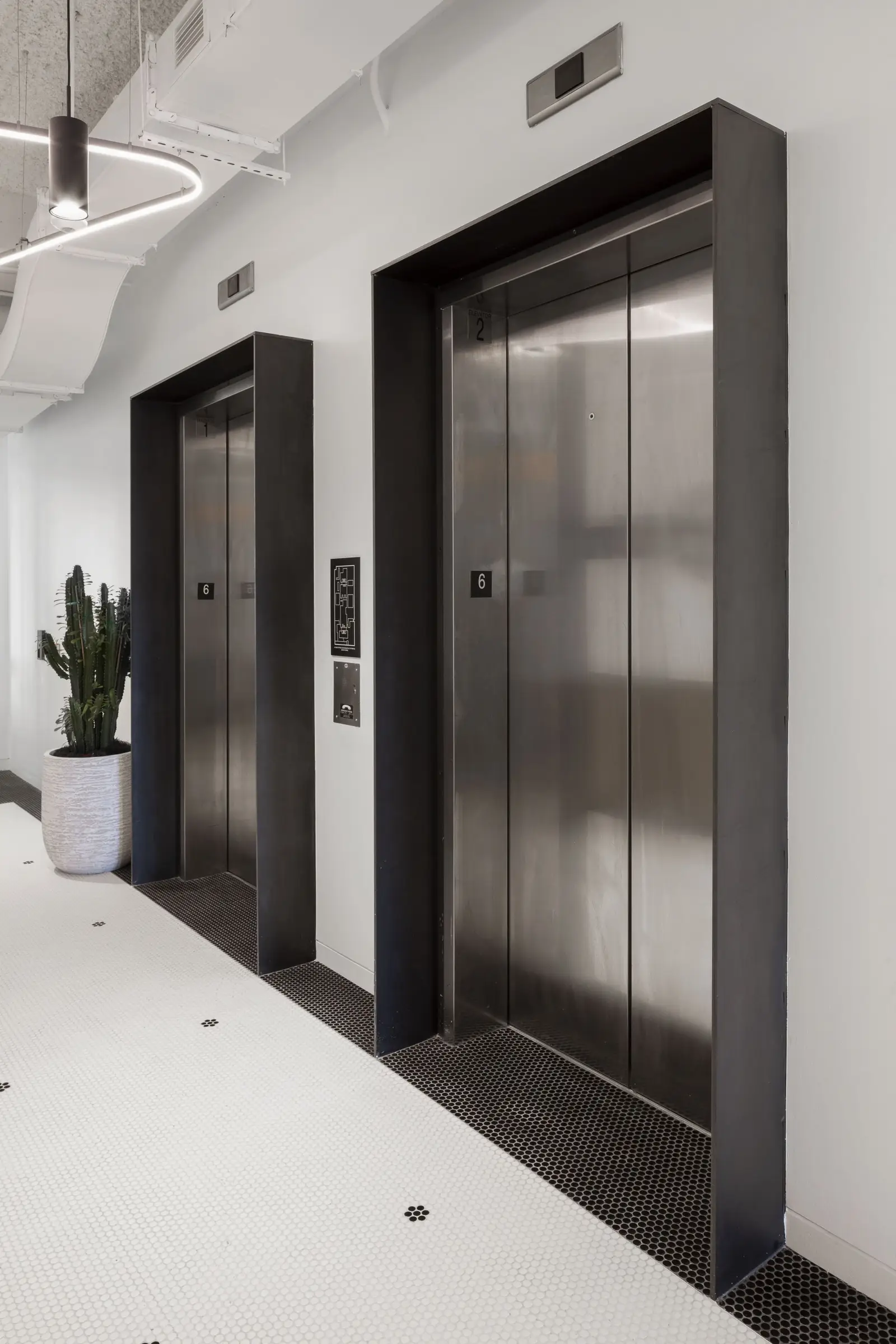 Unity elevators with dark metal frames in a white corridor