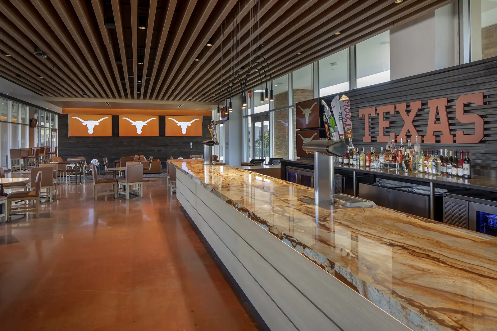 University of Texas South End Zone club bar counter with a wood top and slat ceiling beneath TEXAS signage