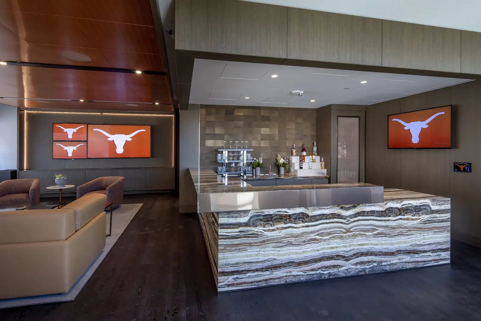 University of Texas South End Zone lounge with a veined stone counter, wood ceiling and Longhorn screens