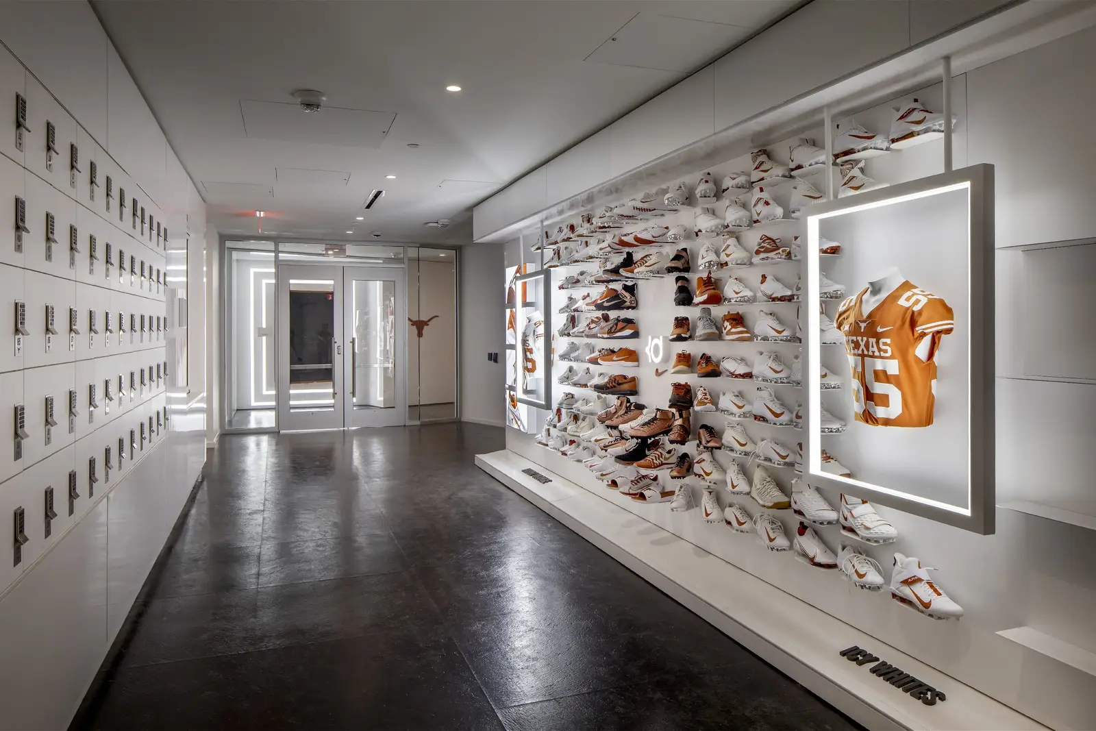 University of Texas South End Zone corridor with lockers and a wall display of shoes and a framed jersey
