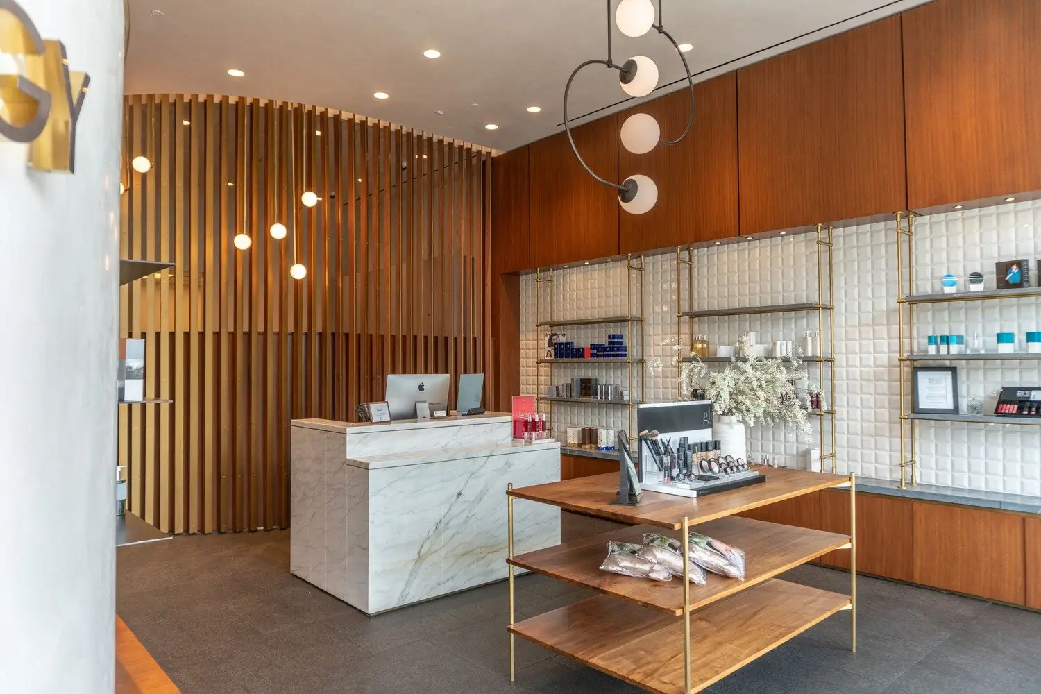 Westlake Dermatology reception with a stone-front desk, a vertical wood slat wall and a display table
