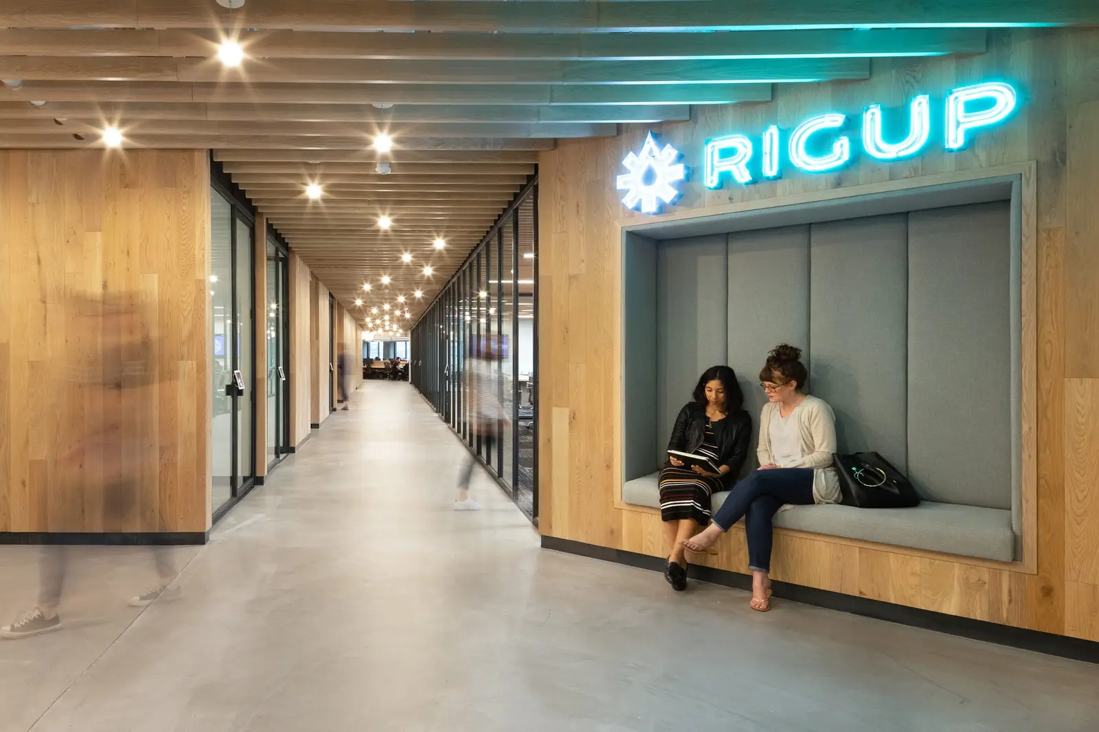 Workrise (formerly Rigup) corridor with a built-in padded seat and a lit sign on a wood wall
