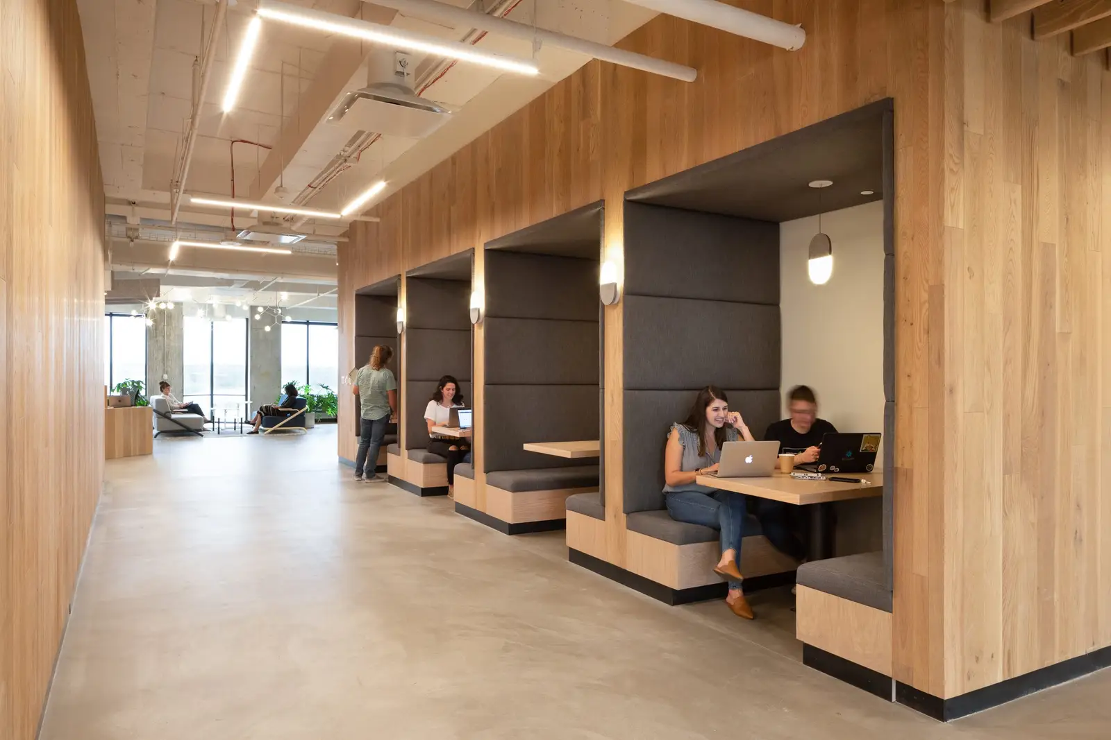 Workrise (formerly Rigup) wood-clad booths with gray upholstery along a corridor