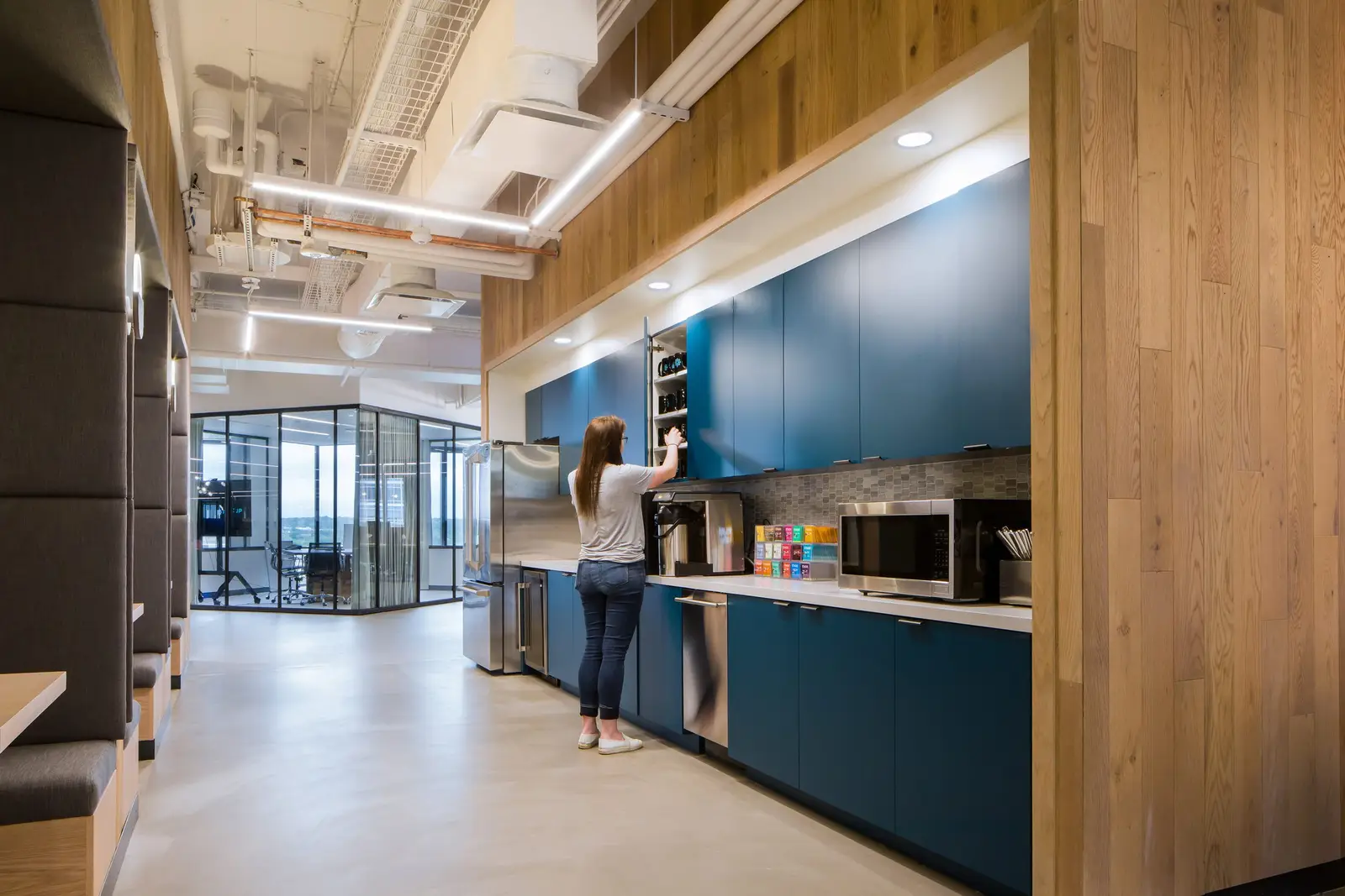 Workrise (formerly Rigup) teal kitchen cabinets and a wood-clad wall in a corridor