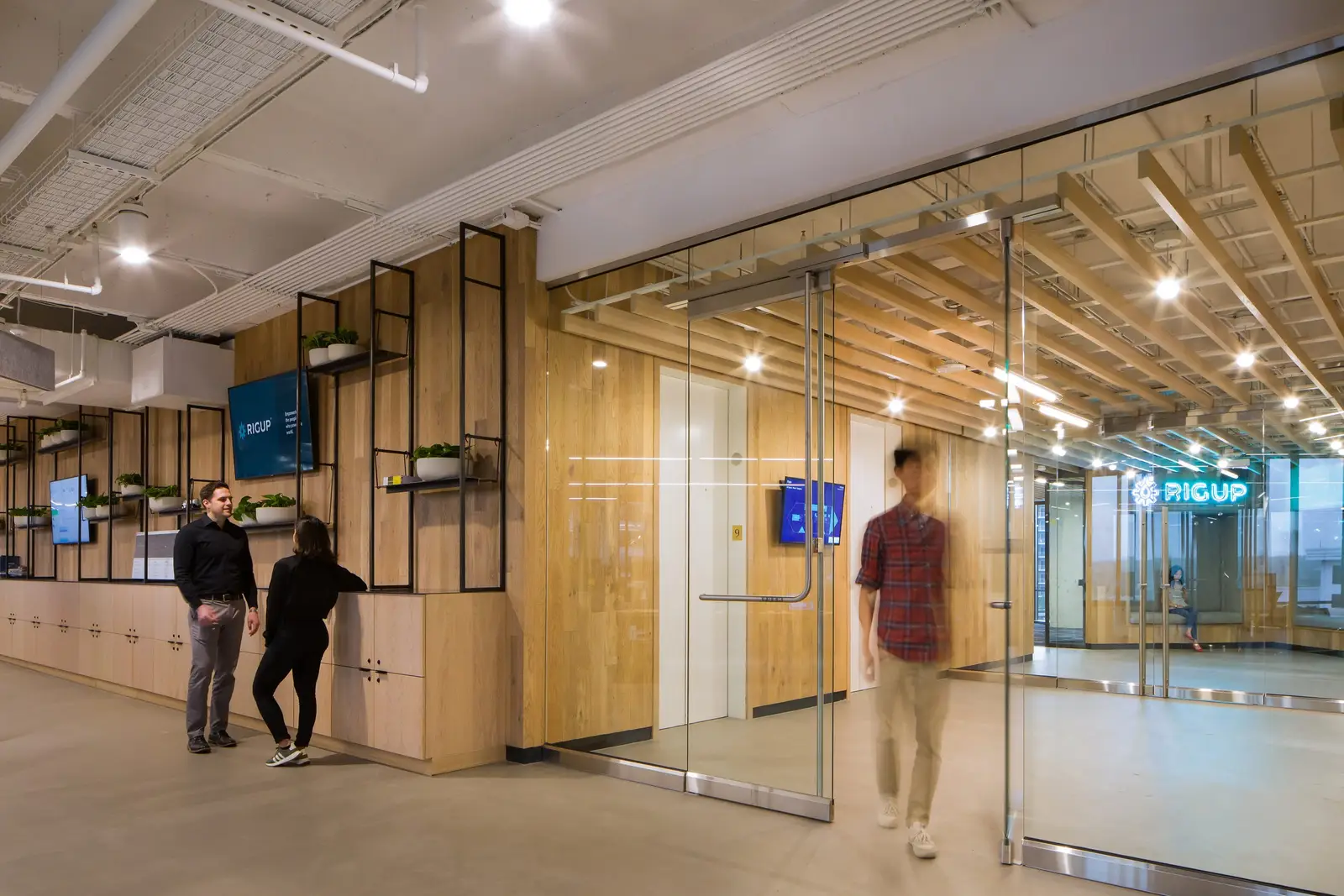 Workrise (formerly Rigup) glass doors in front of a wood wall with metal framework shelving